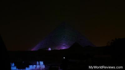The great pyramid lit up in blue, with a laser effect on the front